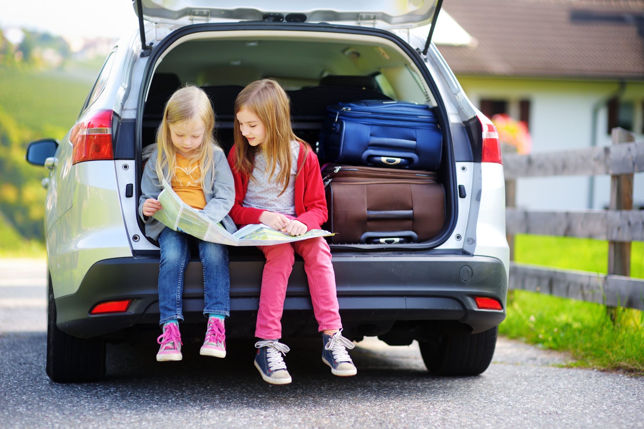 two girls looking at map in open car trunk out of state buyers
