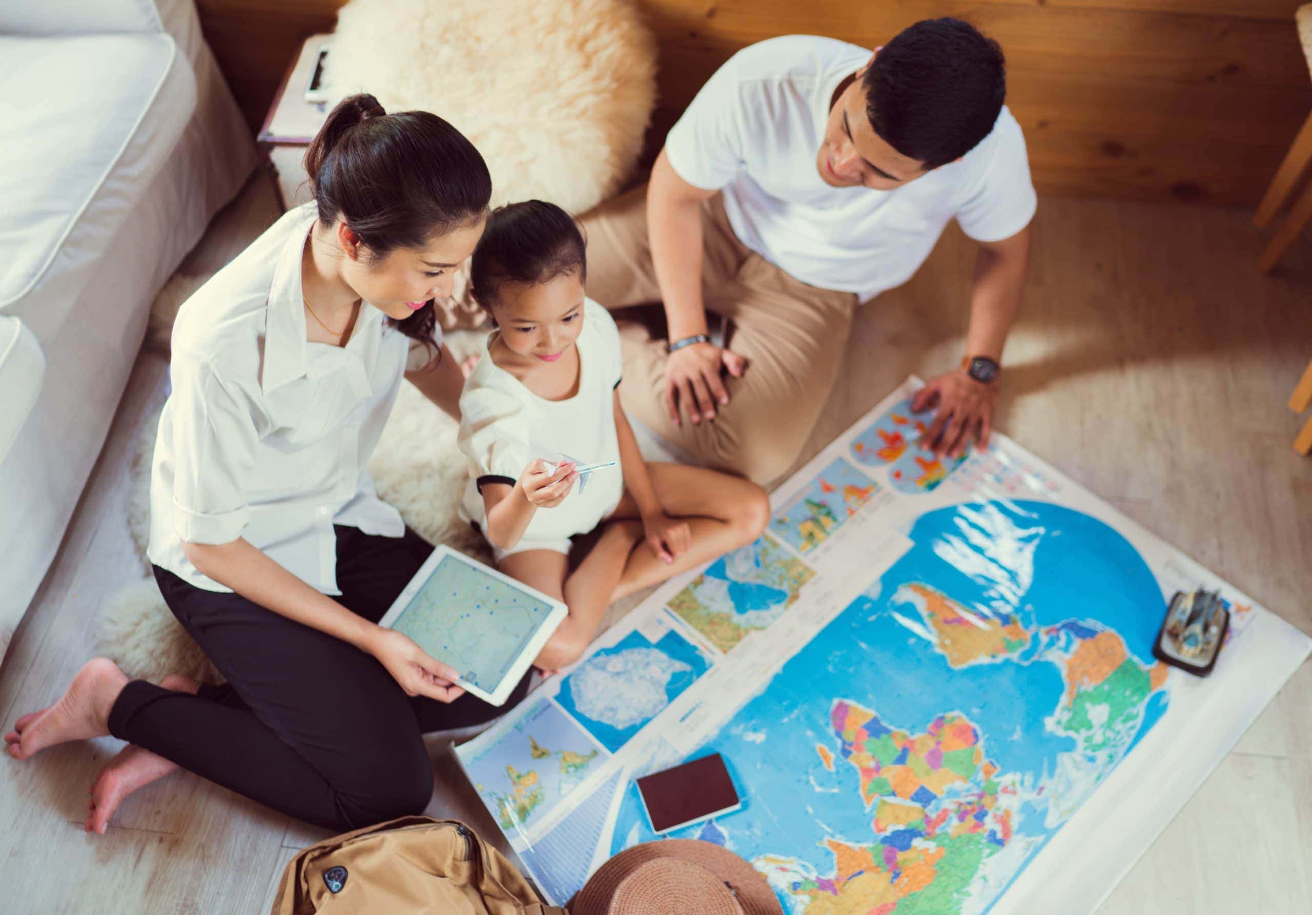 family of three looking at world map to buy a second home