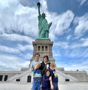five people standing in front of the statue of liberty