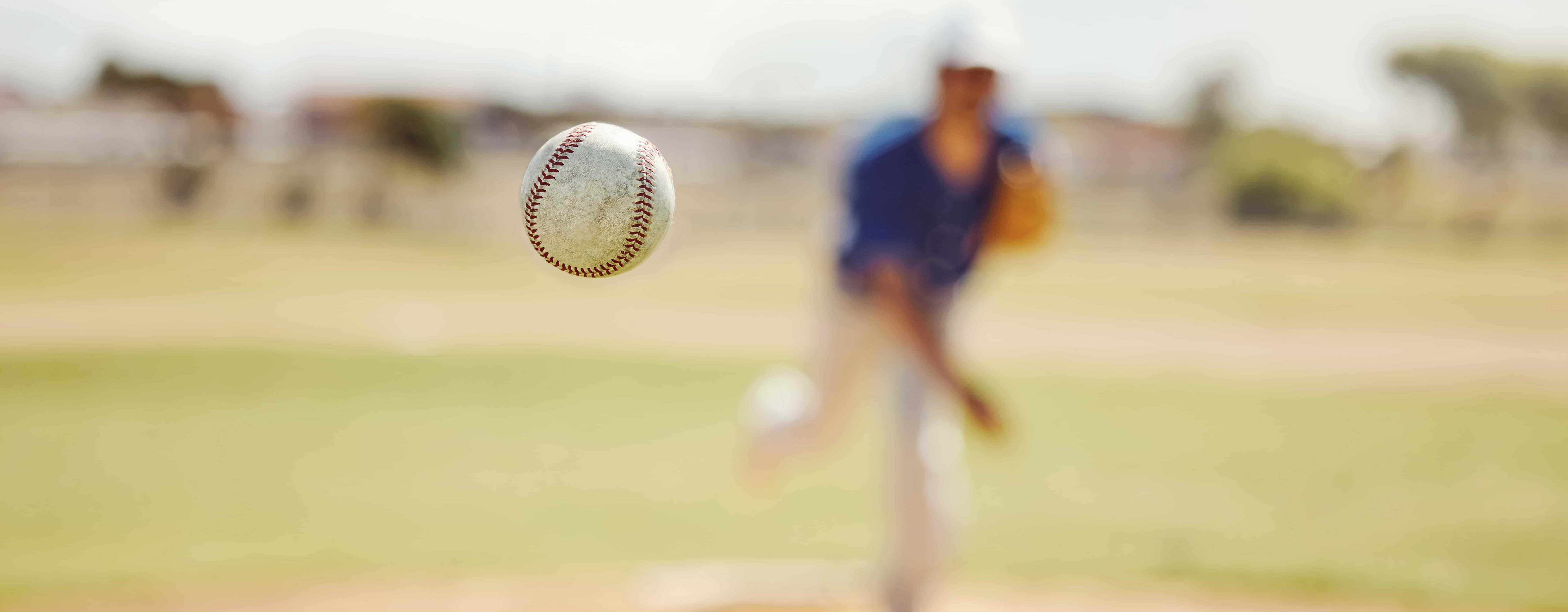 person out of focus throwing baseball that's in focus